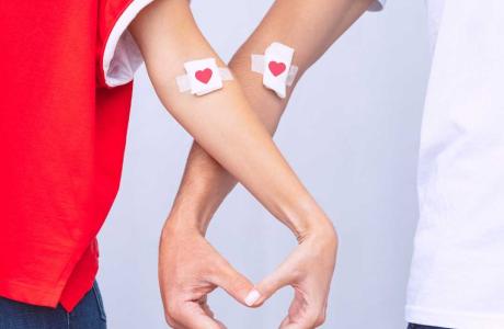 Image of 2 blood donors making a heart with their hands