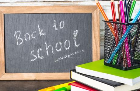 Books and pencils in front of a chalkboard that says back to school