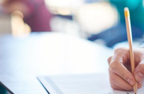 Image of student hand hovering over a test with a pencil