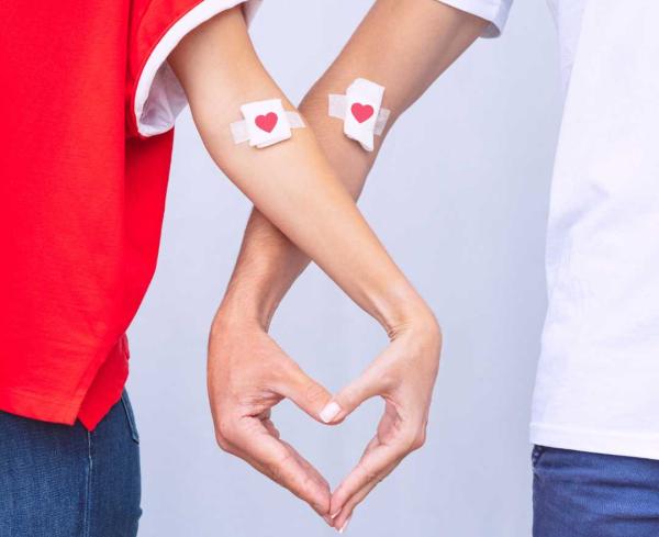 Image of 2 blood donors making a heart with their hands