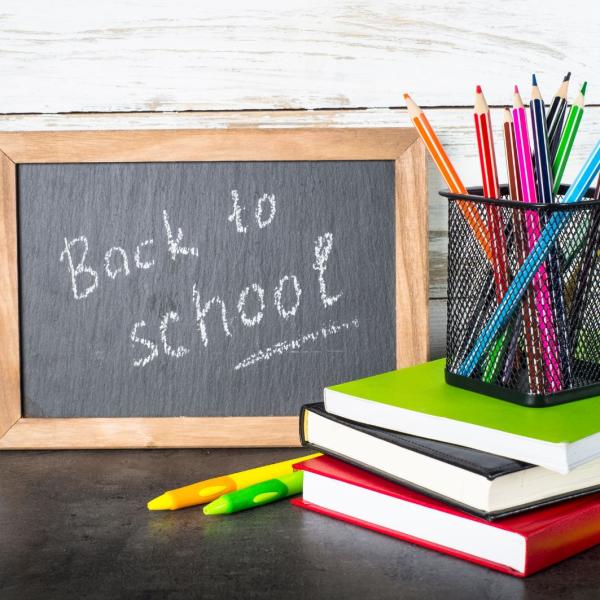 Books and pencils in front of a chalkboard that says back to school