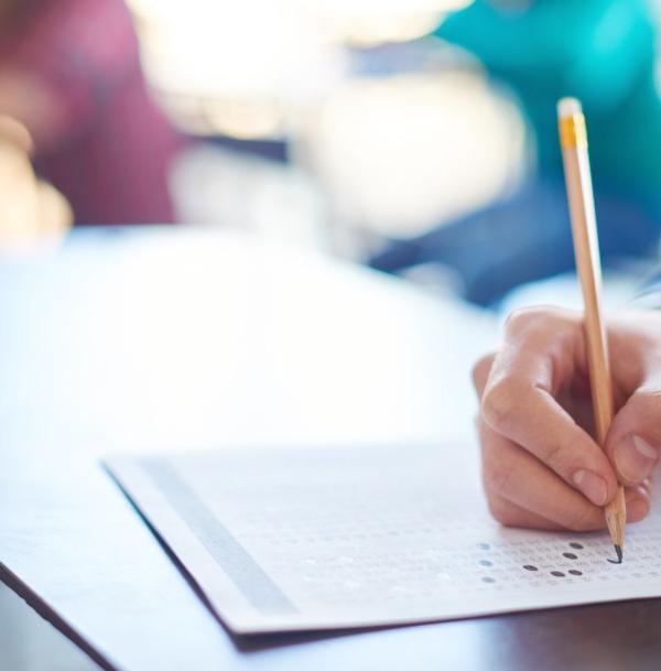 Image of student hand hovering over a test with a pencil