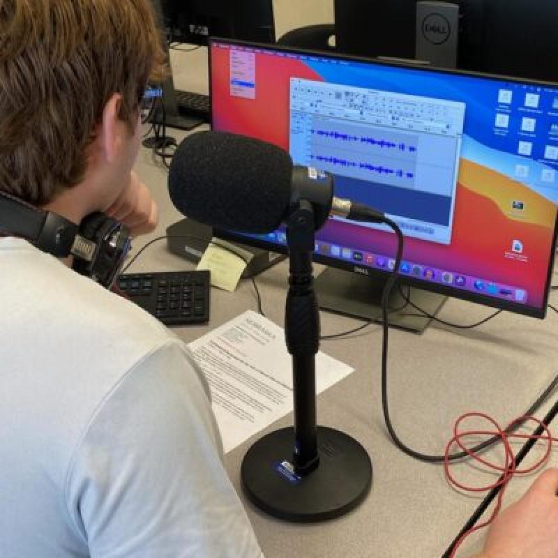 Student with a radio microphone in front of a computer