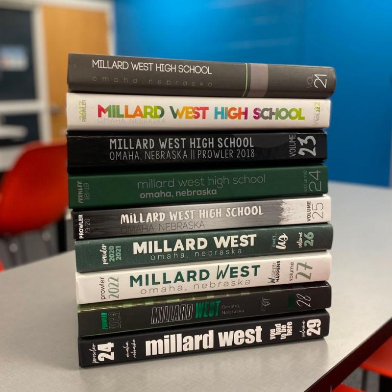 9 Millard West Yearbooks in a stack on a table