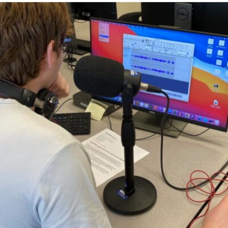 Student with a radio microphone in front of a computer