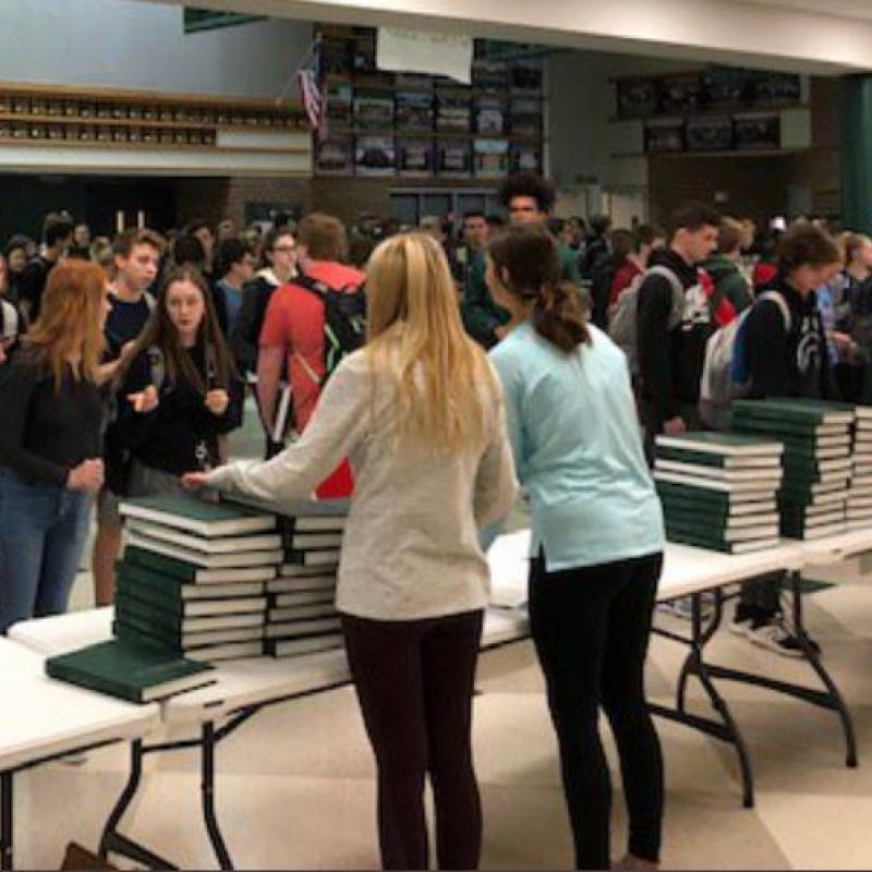 Image of 2 students distributing yearbooks in the MWHS commons